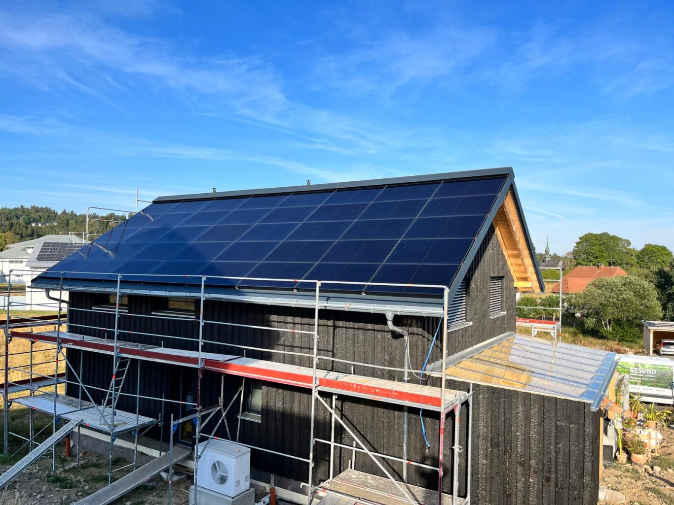 Blechnerarbeiten, Einfamilienhaus Holzhaus mit schwarzer Fassade und Gerüst, Dachrinnen aus Titanzink und Anschlussbleche aus farbbeschichtetem Aluminium